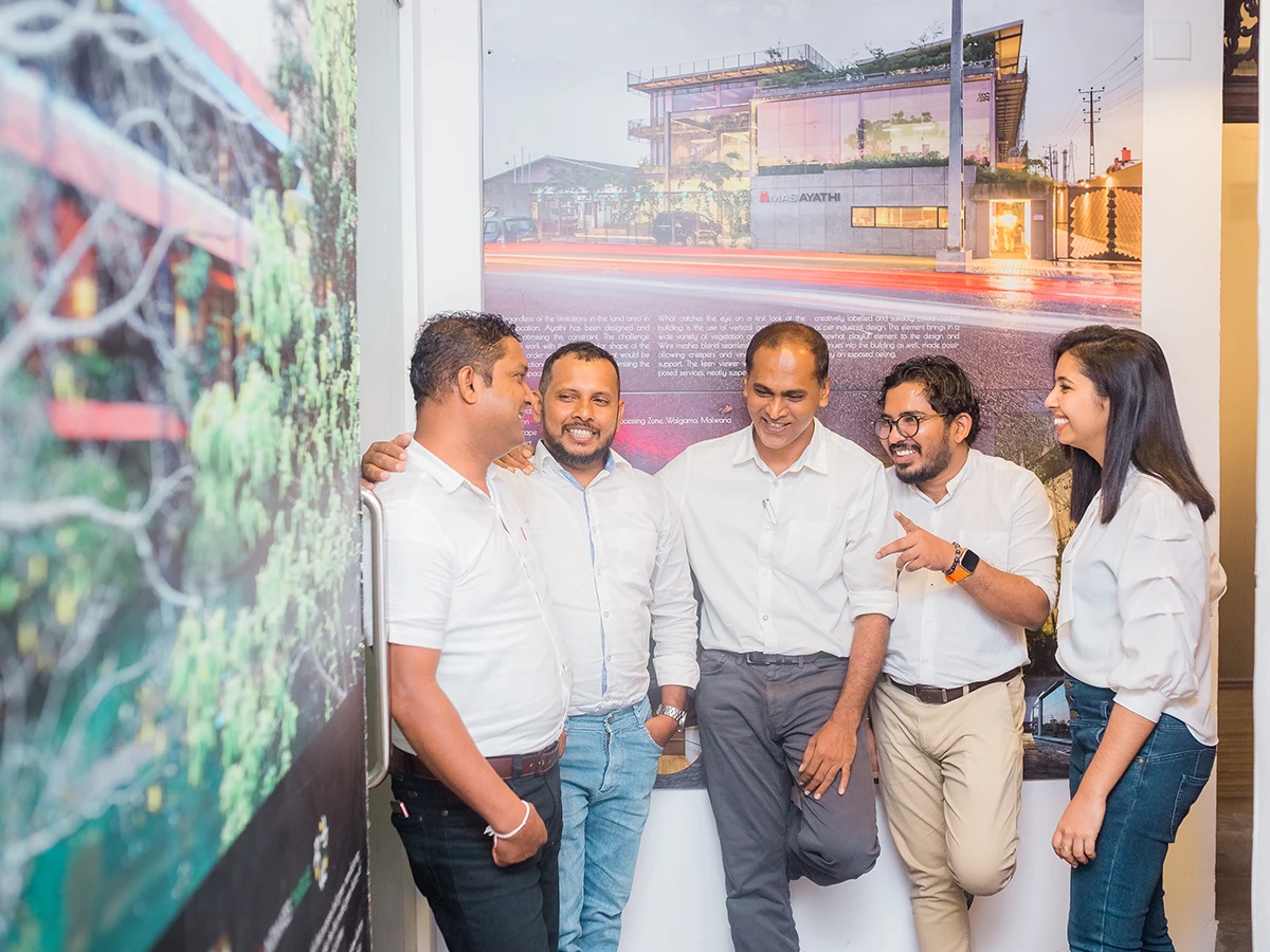 The team in front of a large print of one of their projects